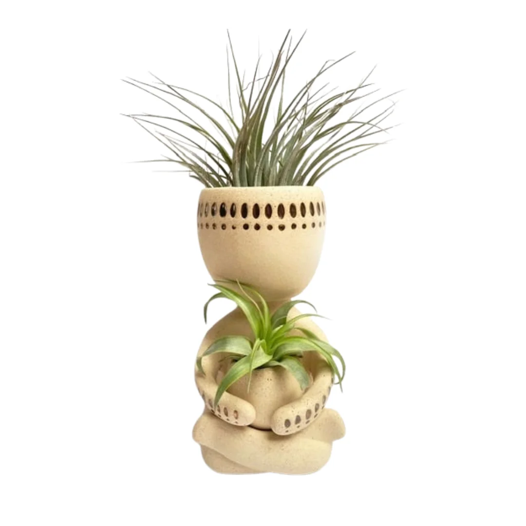 Zittend zandkleurig keramiek airplant poppetje met een Tillandsia luchtplant in het hoofd en in de handen